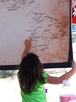 picture of back of young girl pointing to an island on a large map