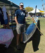 picture of man standing between canoe club display and the canoe